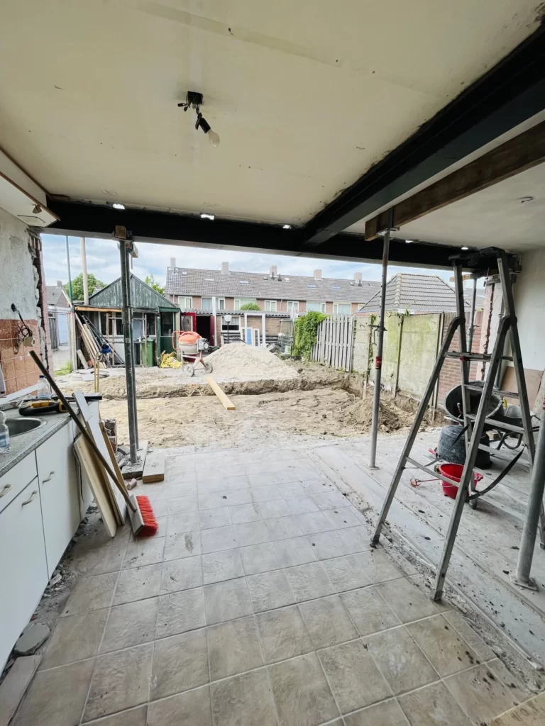 Brede doorbraak in de achtergevel met een zwarte stalen ligger, nog op stempels