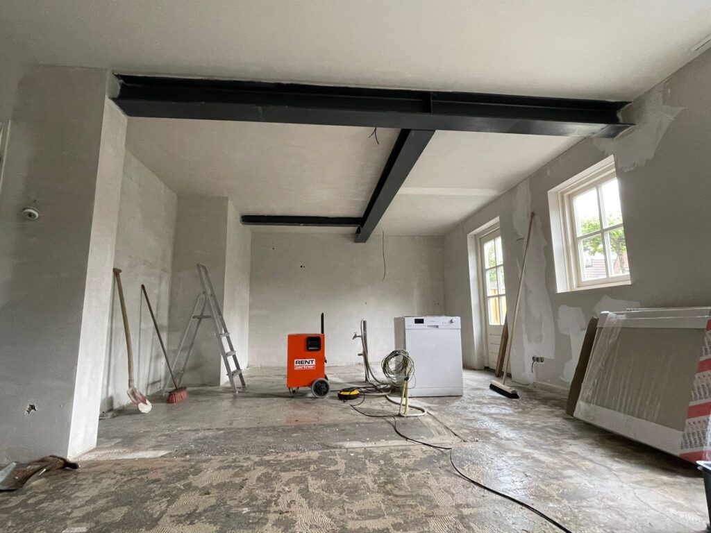 Lege ruimte met nieuwe zwarte stalen liggers onder het plafond, klaar voor de afwerking