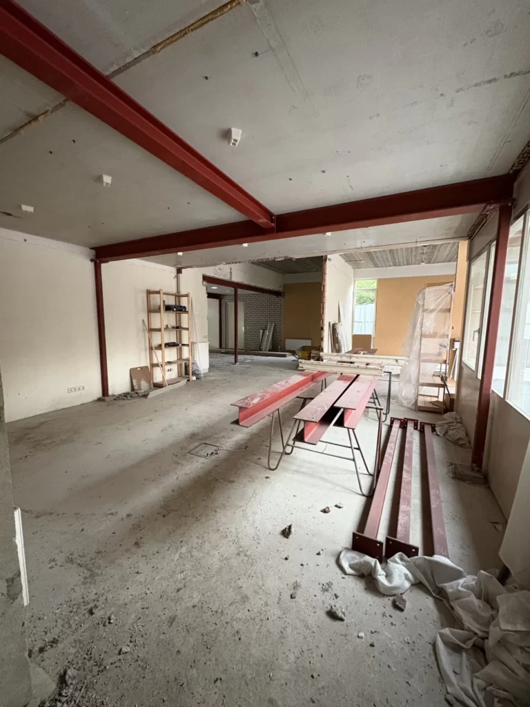 Rood gegronde stalen liggers op de vloer, klaar voor plaatsing